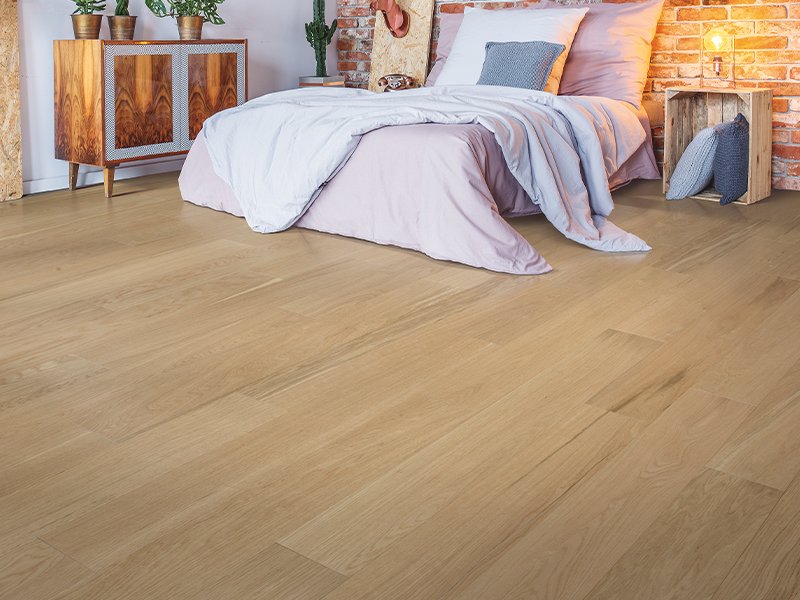 white bed on brown hardwood in West Suite F Clayton, NC area by by Clayton Flooring Center